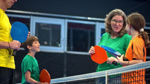 Video Two adults and two children talking after playing pickleball on a blue, inside court - Starpik Stock