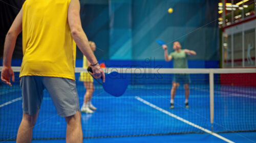 Video Two men and two women playing pickleball on a blue, inside court - Starpik