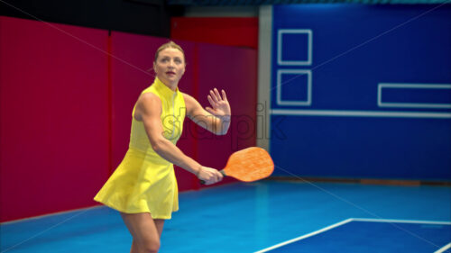 Video Woman in a yellow dress playing pickleball on a blue, inside court - Starpik