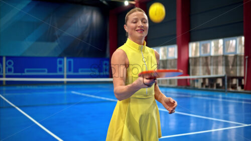 Video Woman in a yellow dress training to play pickleball on a blue, inside court - Starpik