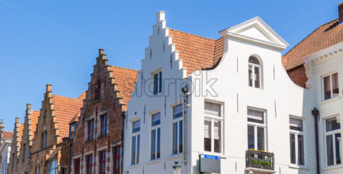 View from bottom to local old buildings. Bright blue sky on background. Place for text. Bruges, Belgium - Starpik