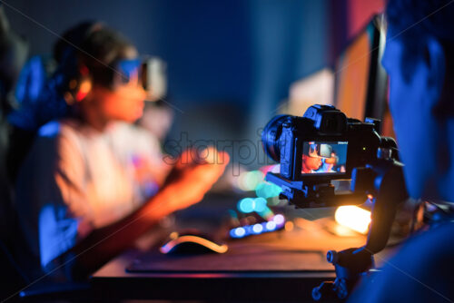 View of a professional photographer filming teens in VR headsets playing video games in video game club - Starpik