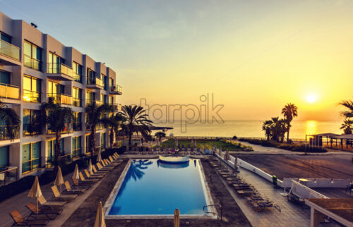 View to warm sunrise above hotel resort. Pool, palm trees, boat and sea on background. Negative copy space, place for text, Protaras, Cyprus - Starpik