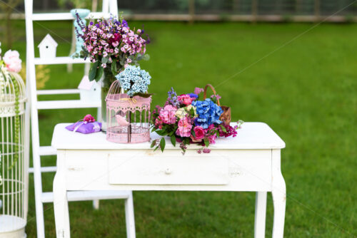 Vintage wedding decoration with white table, flowers and parrot cage. - Starpik