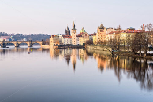 Vltava River, Charles Bridge and famous clocktower near castle at sunset. Buildings reflecting on water. Clouds on sky. Negative copy space, place for text. Prague, Czech Republic - Starpik