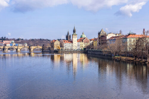 Vltava River, Charles Bridge and famous clocktower near castle. Buildings reflecting on water. Clouds on sky. Negative copy space, place for text. Prague, Czech Republic - Starpik