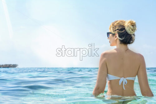 Woman in the sea, Cyprus. Beautiful Summer seaside view. Enjoying sunny day. Shot from behind - Starpik