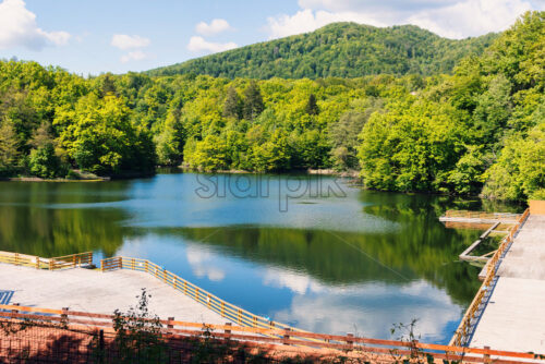 Wooden relaxing area on the sovata lake in romania, rest area surrounded by historic forested mountains, rainy day, fog and reflection, near salt mine - Starpik