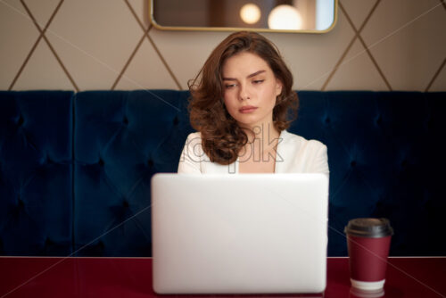 Young cute girl working on laptop in cafe. Coffee on the table - Starpik