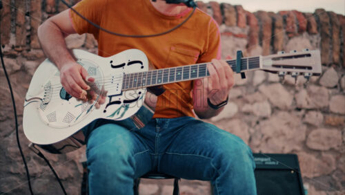 video Close up of a man playing a golden esonator guitar on the street - Starpik Stock