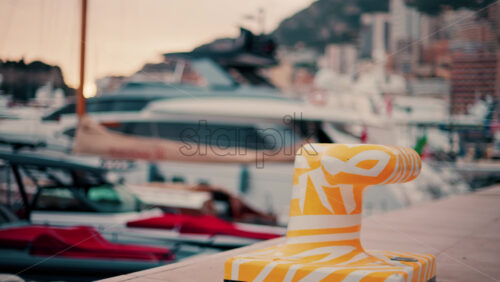 video Close up of a white and yellow dock cleat in a harbour with boats on the background - Starpik Stock