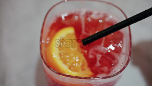 video Close up of a woman mixing a red cocktail with a black straw - Starpik Stock