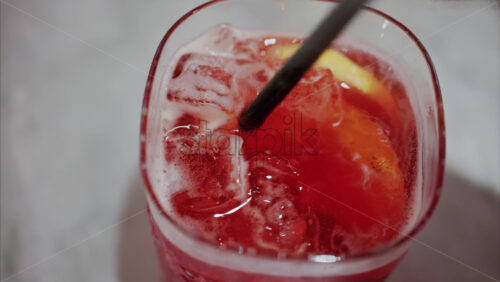 video Close up of a woman mixing a red cocktail with a black straw - Starpik Stock