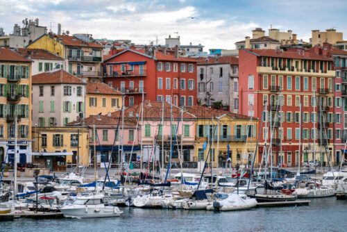 Red and orange buildings in Nice, France, boats and yachts at the Lympia port, green trees - Starpik Stock